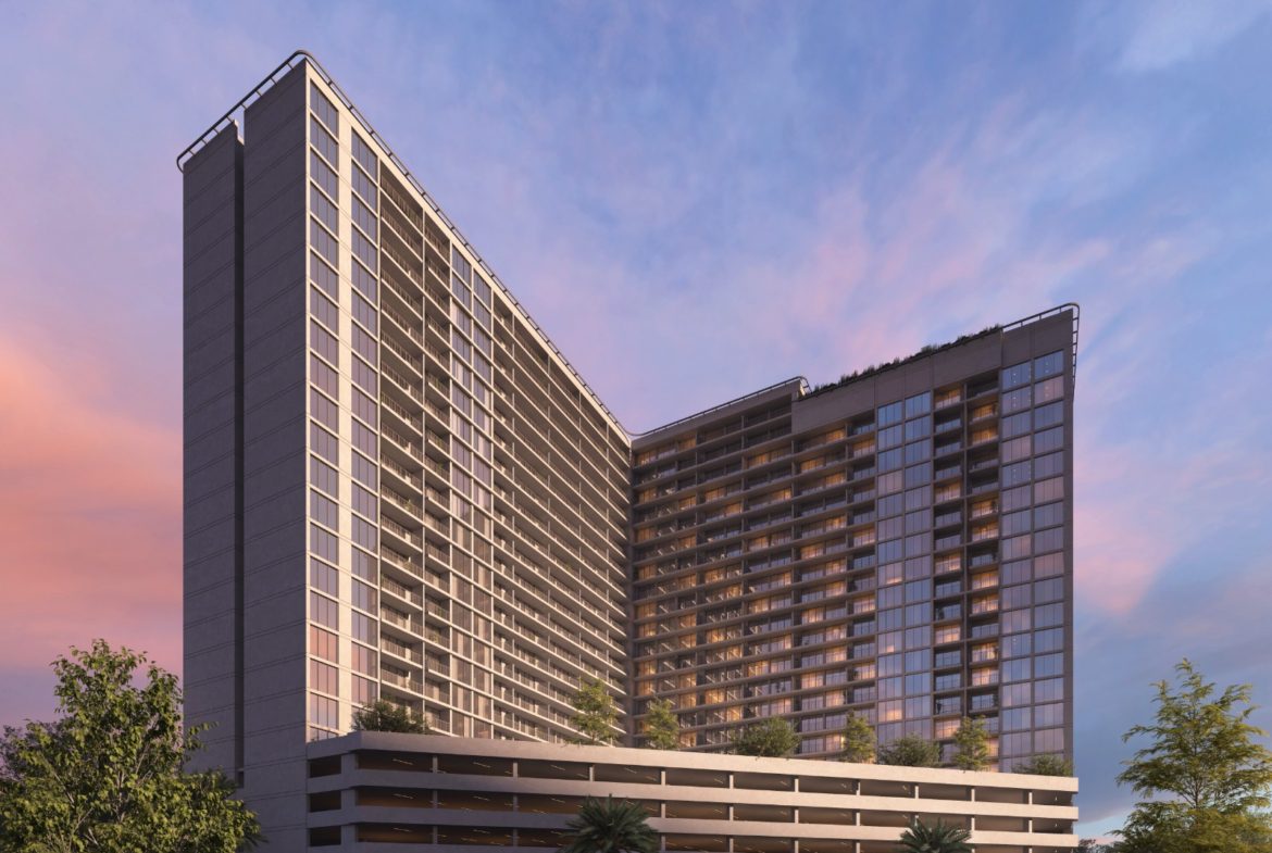 Exterior view of Luma Park Views tower, featuring expansive glass windows and lush greenery, set against a clear blue sky